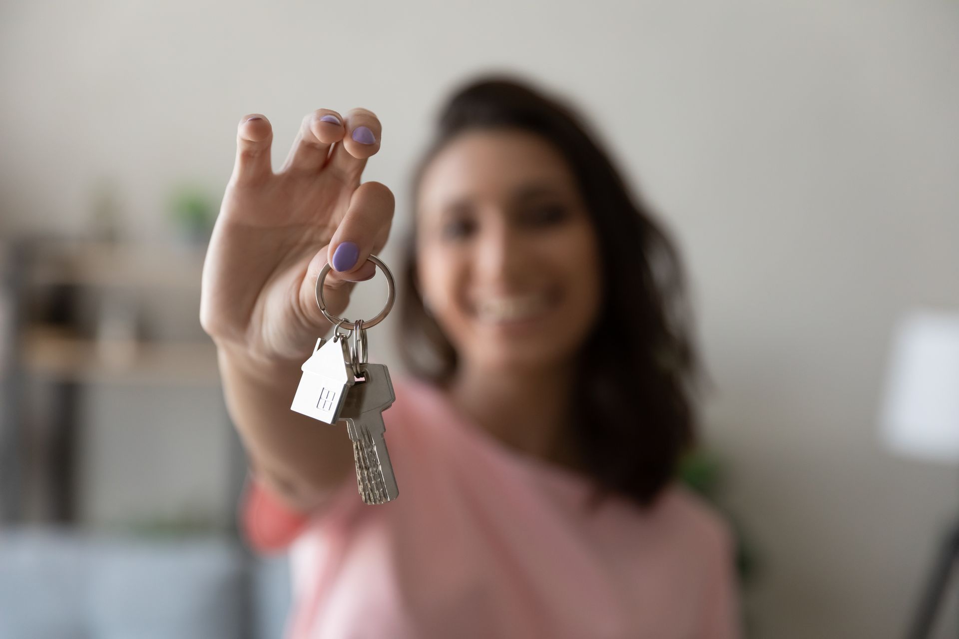 a woman in a pink shirt is holding up a set of house keys