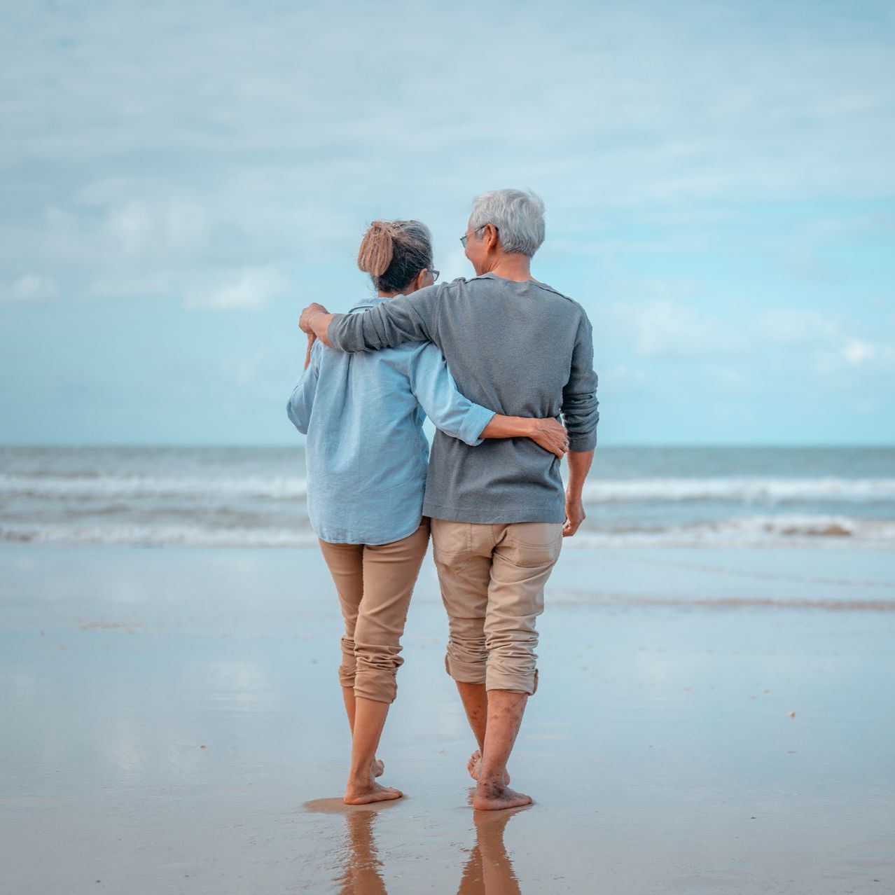 a man and woman standing on a beach looking at the ocean