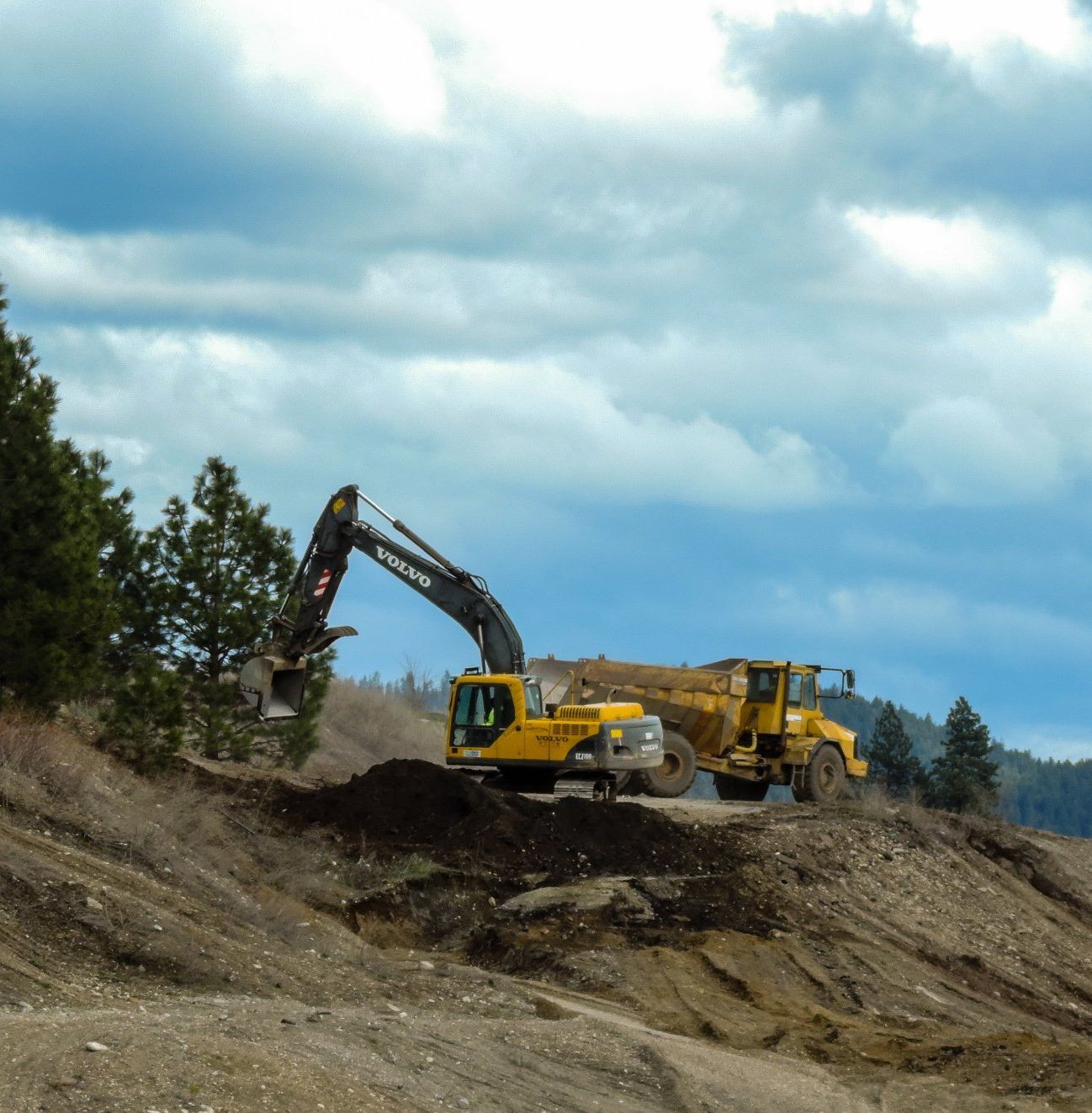 A volvo excavator is working on a dirt road