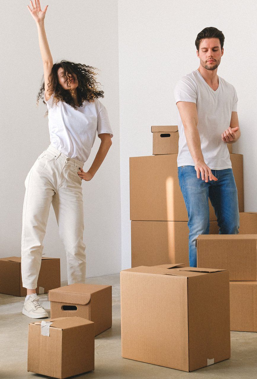 A man and a woman are jumping in the air while sitting on cardboard boxes.