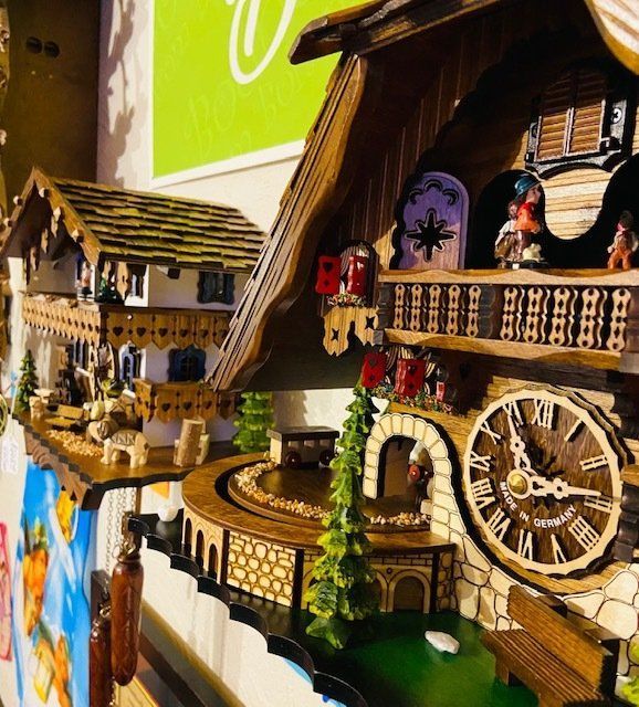 Handcrafted wooden cuckoo clocks with carved balconies and a large clock face on display