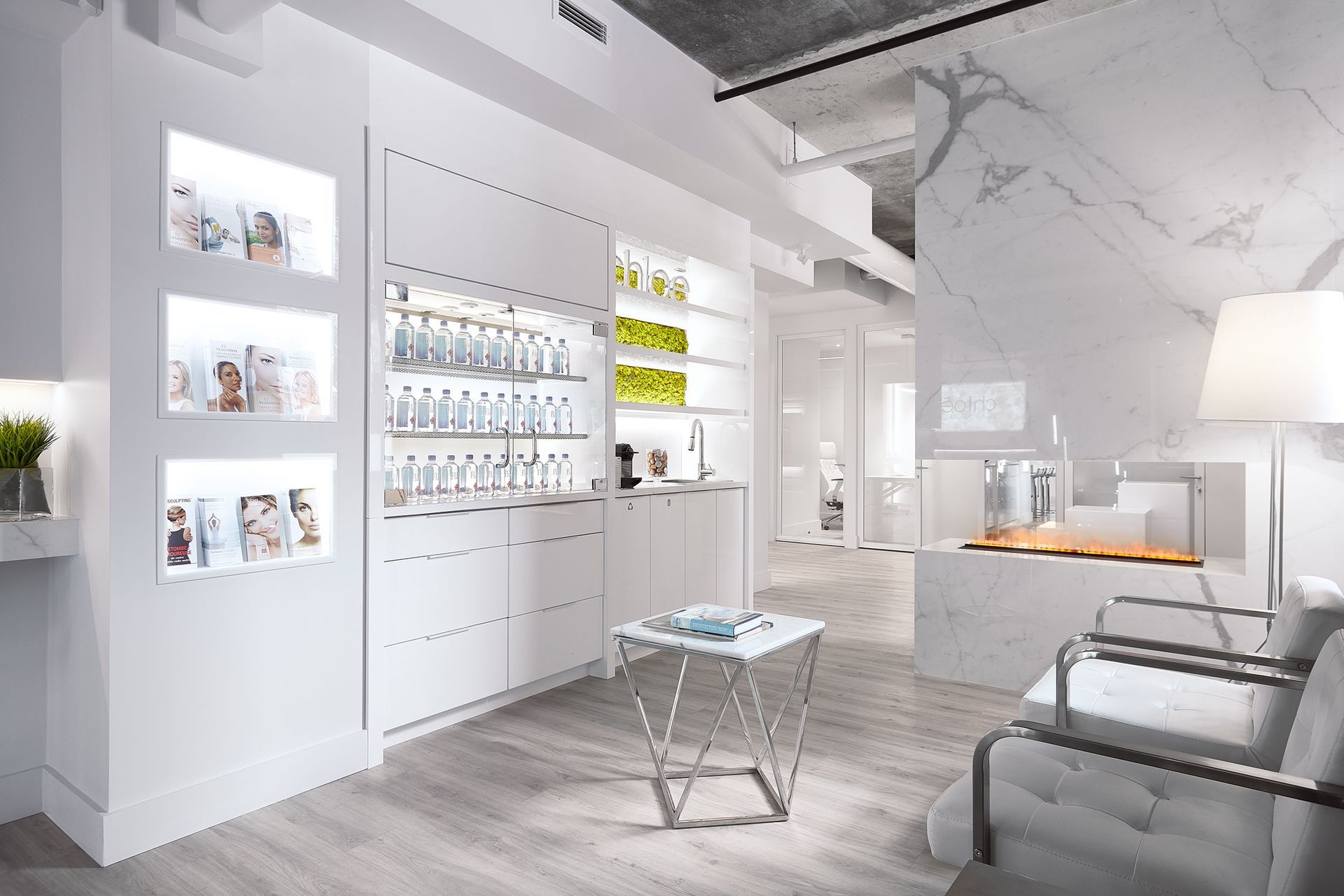 Intérieur de spa blanc moderne avec présentoirs de produits, chaises et fausse cheminée.