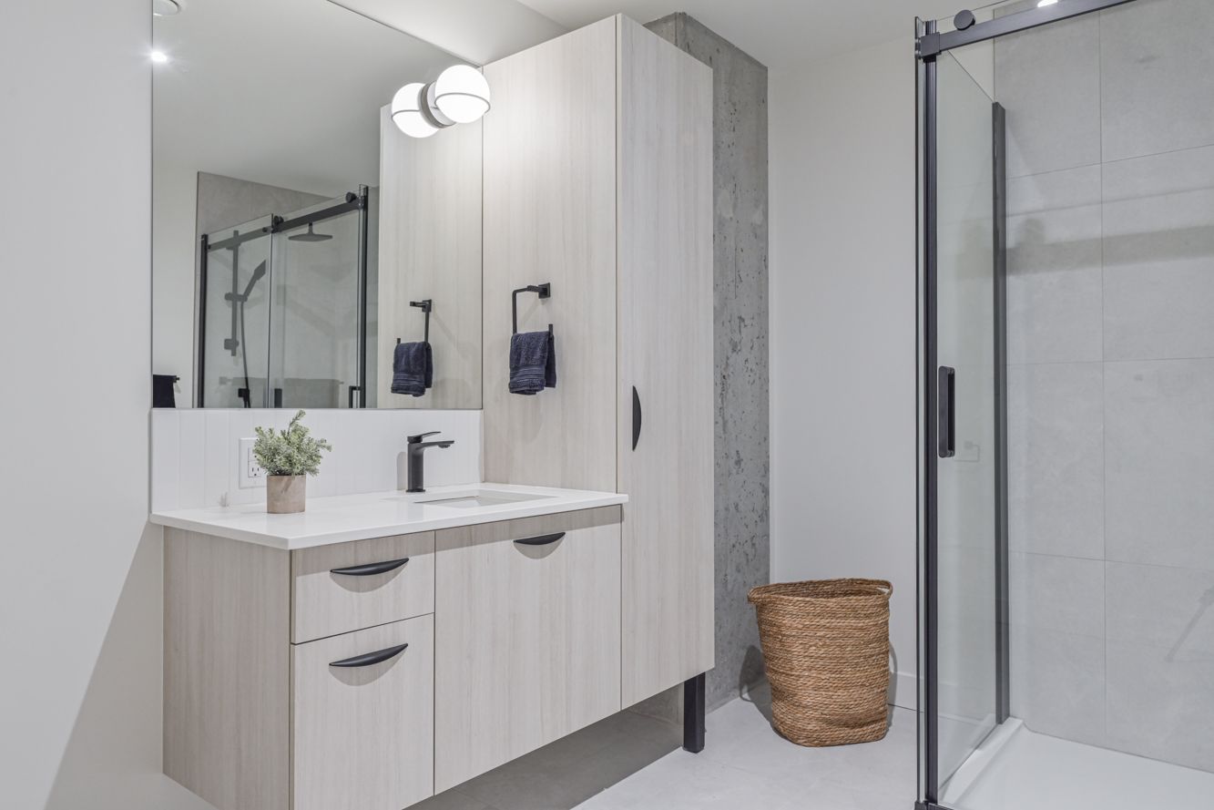 Une femme rousse travaille sur un ordinateur portable, en consultant un plan. Une tasse de café et des papiers sont posés sur la table.