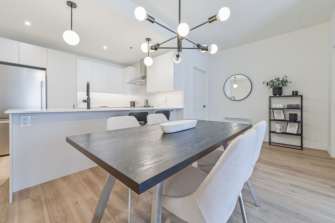 Une femme rousse travaille sur un ordinateur portable, en consultant un plan. Une tasse de café et des papiers sont posés sur la table.