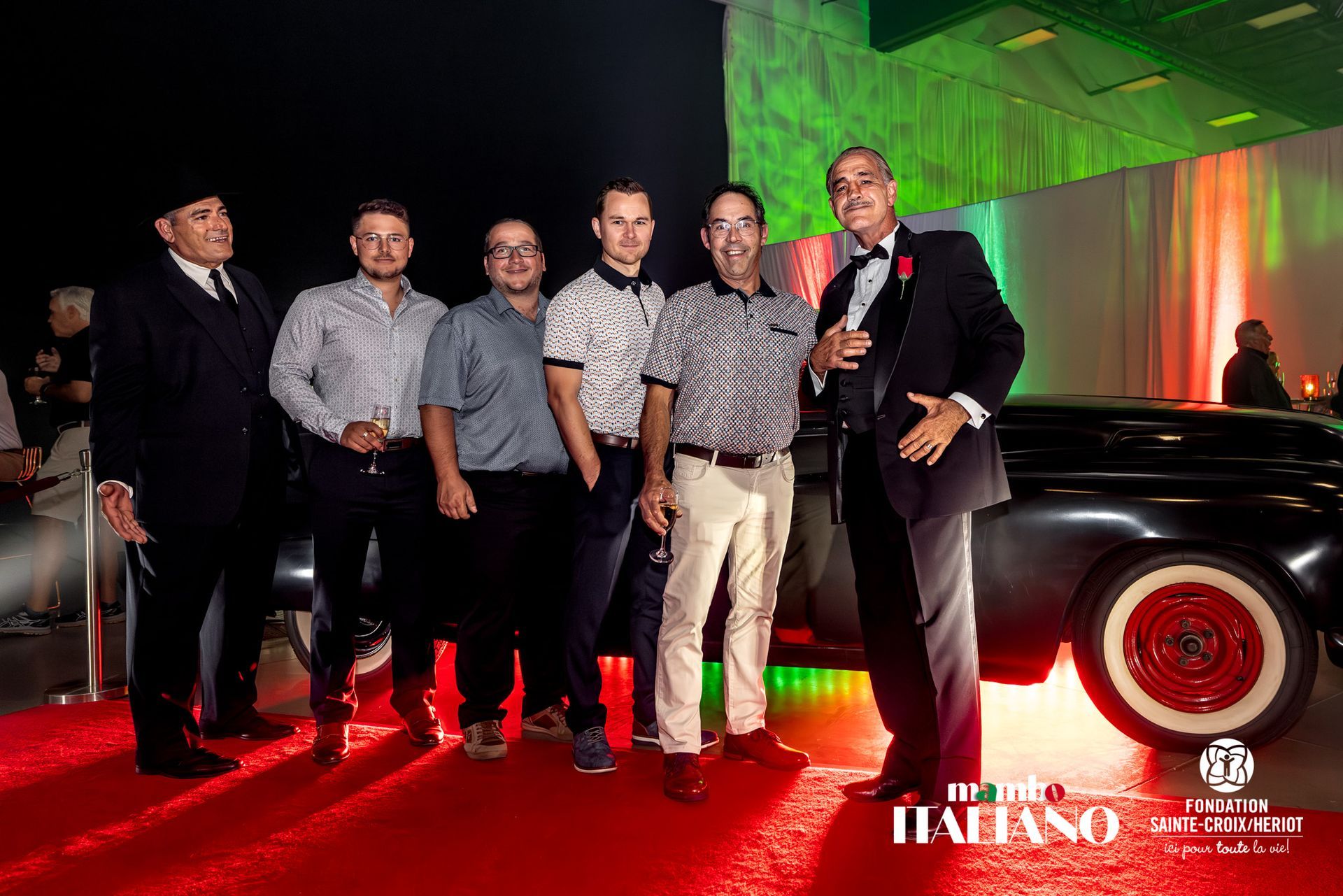 Un groupe d'hommes pose pour une photo devant une voiture.