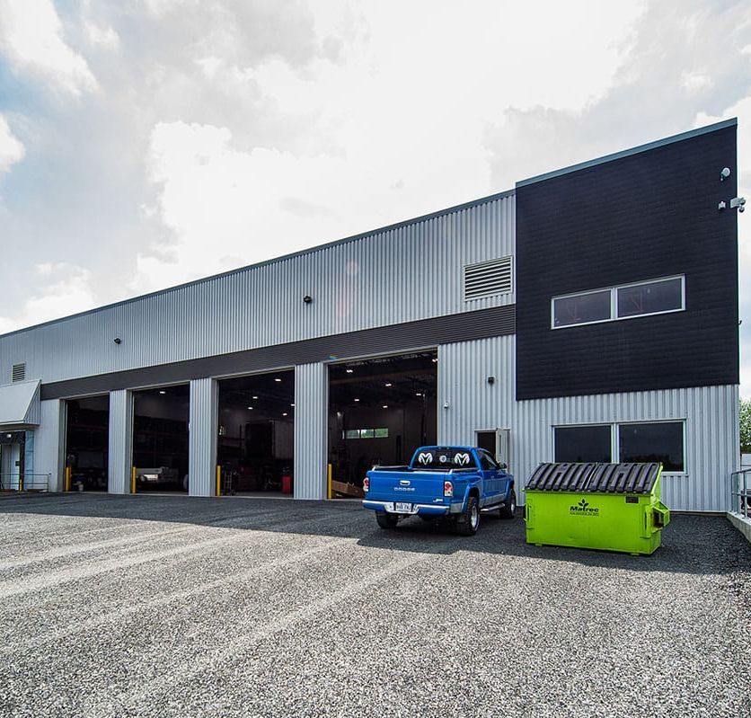 Un camion bleu est garé devant un grand bâtiment