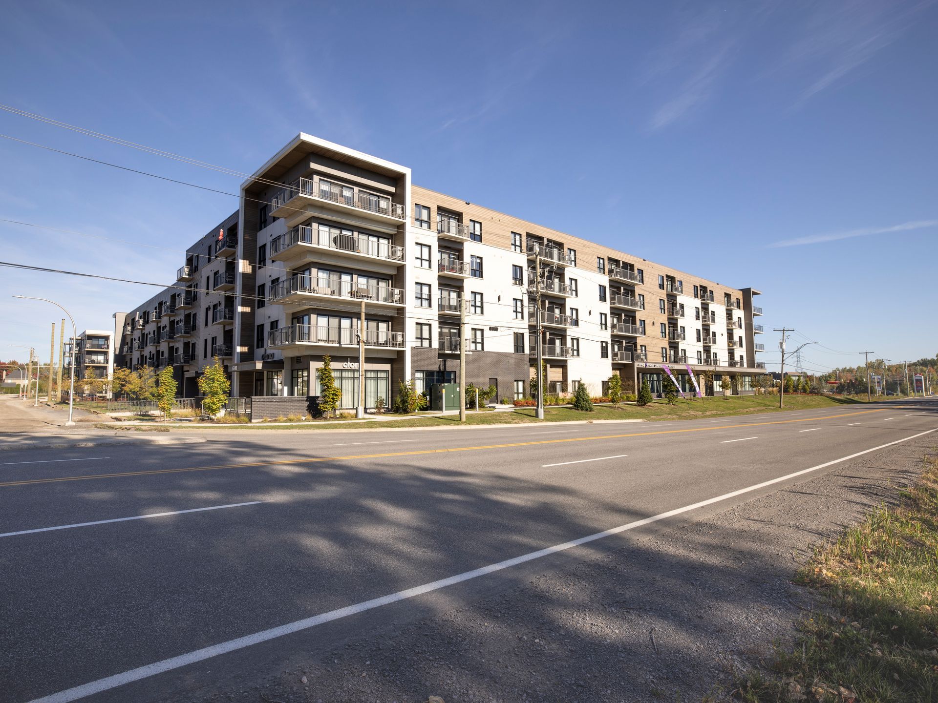 Un grand bâtiment en briques avec beaucoup de fenêtres est entouré d'arbres et d'herbe.