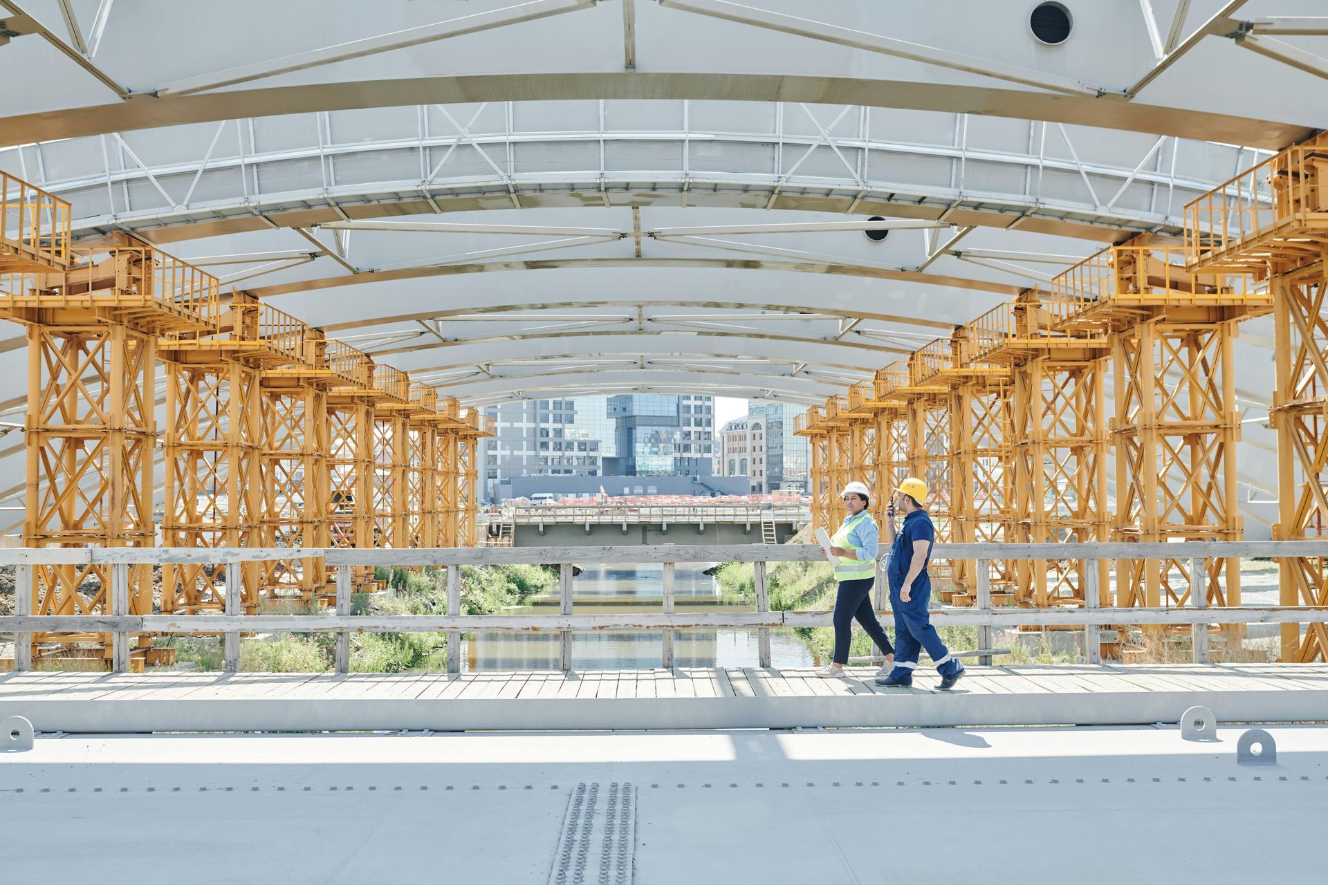 Deux ouvriers du bâtiment traversent un pont en construction.