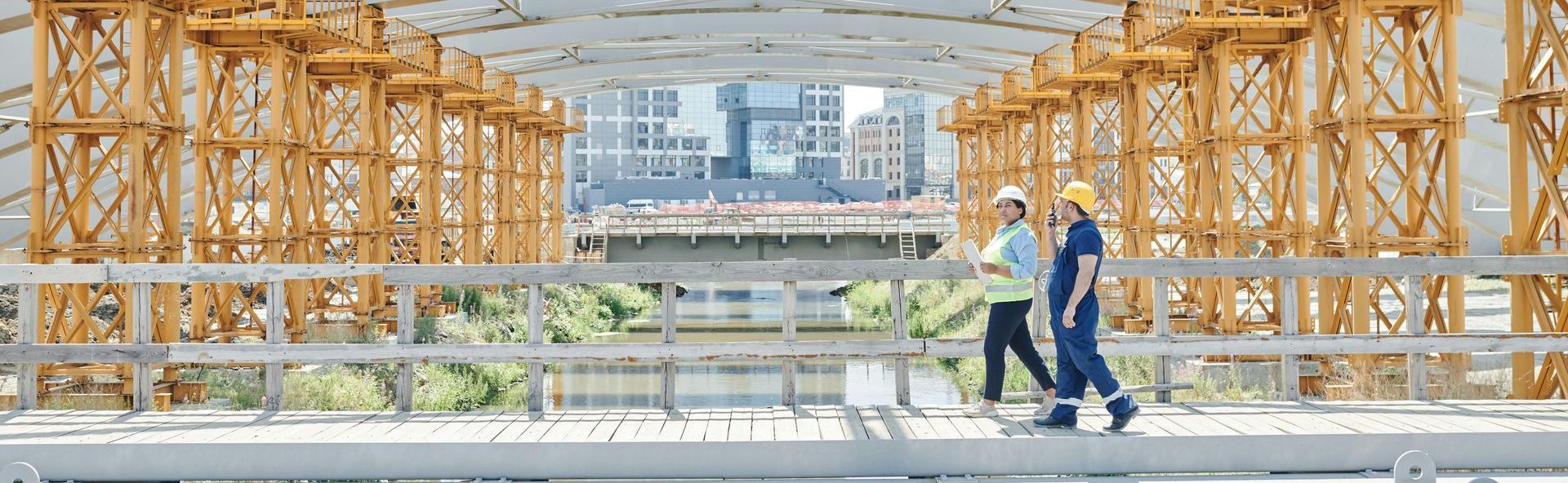 Deux ouvriers du bâtiment traversent un pont sur un chantier de construction.