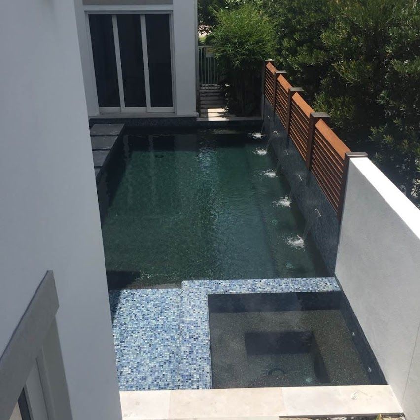 Pool with blue tile, fountains, and a wooden fence.