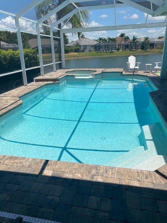 Swimming pool with blue water under a white screened enclosure, sunny outdoor setting.