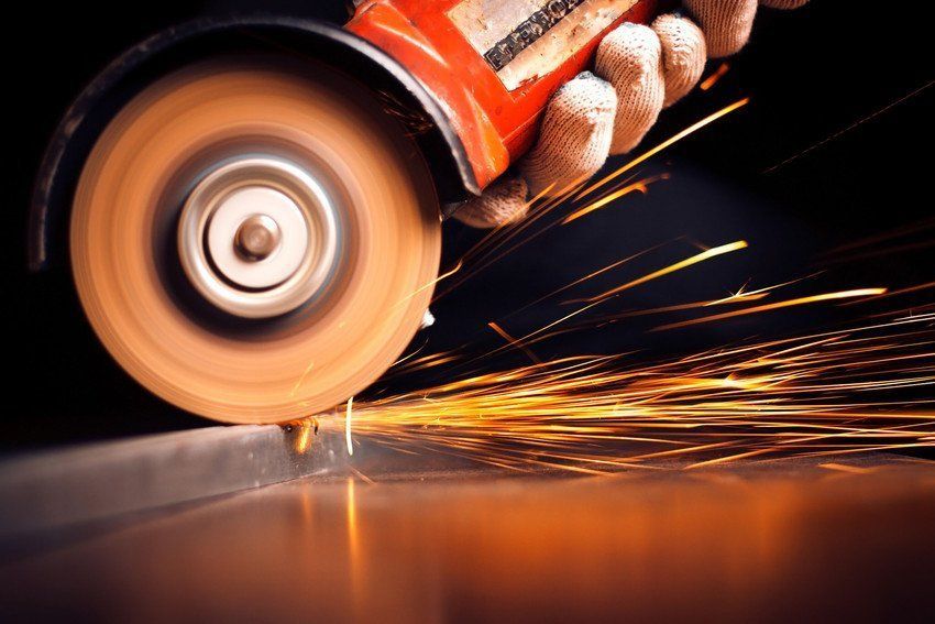 A person is using a grinder to cut a piece of metal.