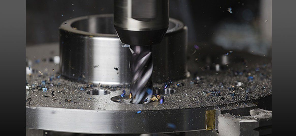 A machine is cutting a piece of metal with a drill bit.