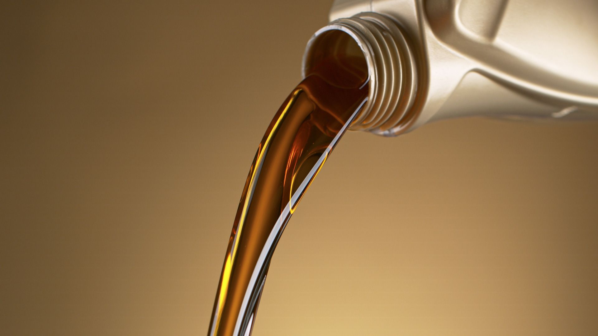 A close up of a bottle of oil being poured into a container.