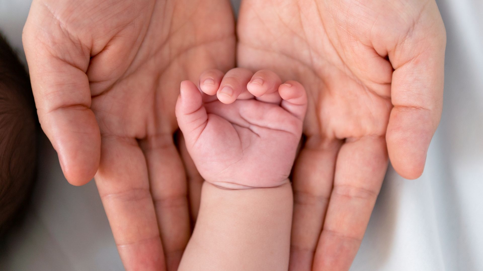 A woman is holding a baby 's hand in her hands.