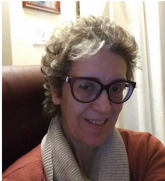 A woman wearing glasses and a scarf smiles for the camera