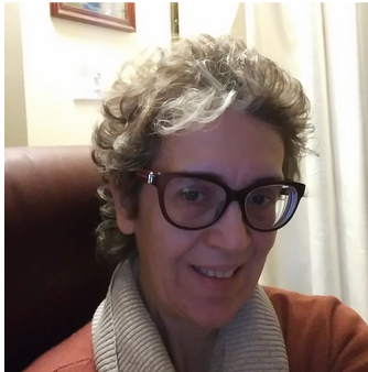 A woman wearing glasses and a scarf smiles for the camera