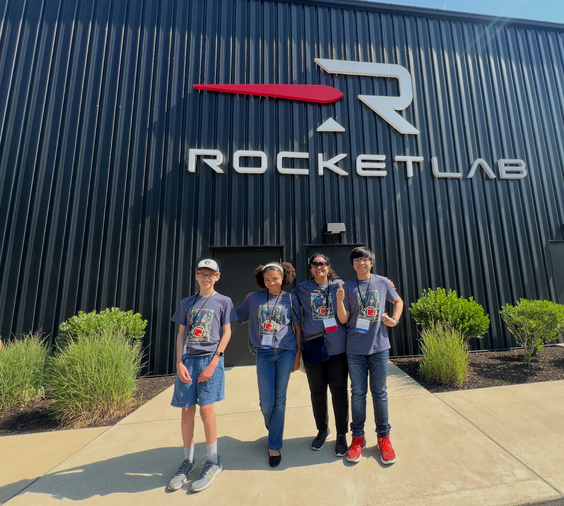 A group of people standing in front of a building that says rocketlab