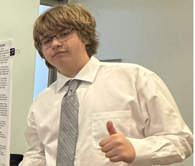 A young man in a white shirt and tie is giving a thumbs up