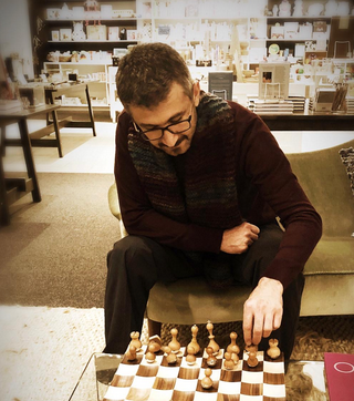 A man is playing a game of chess on a glass table