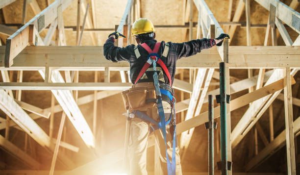 Carpenter wearing safety harness on wood roof frame