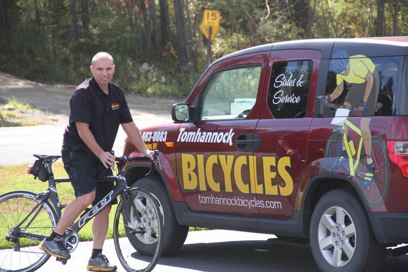 A Man Standing Next to a Bicycle in Front of a Van