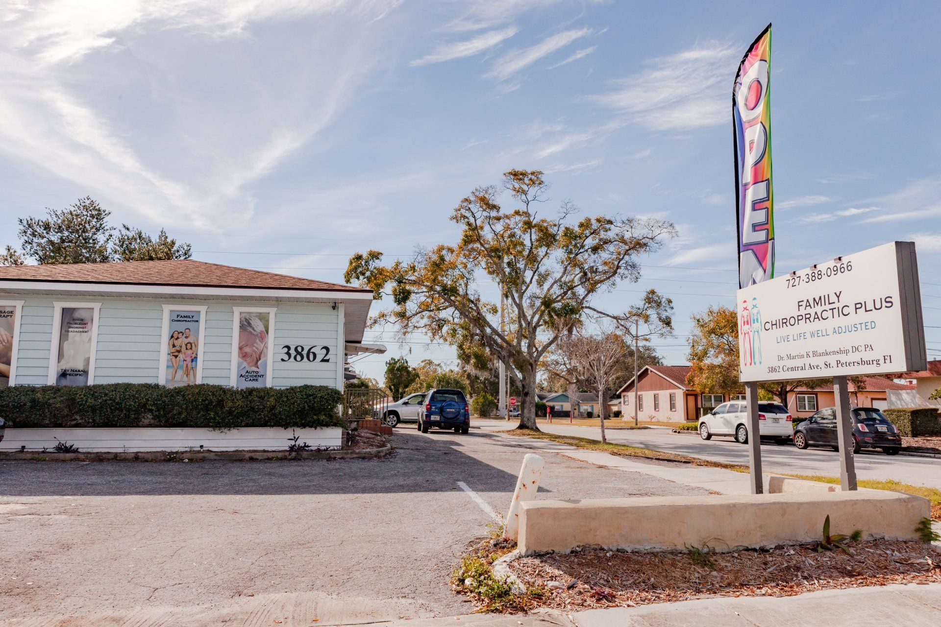 A building with a sign in front of it and a tree in the background.