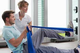 A man is doing exercises with a resistance band while a woman watches.