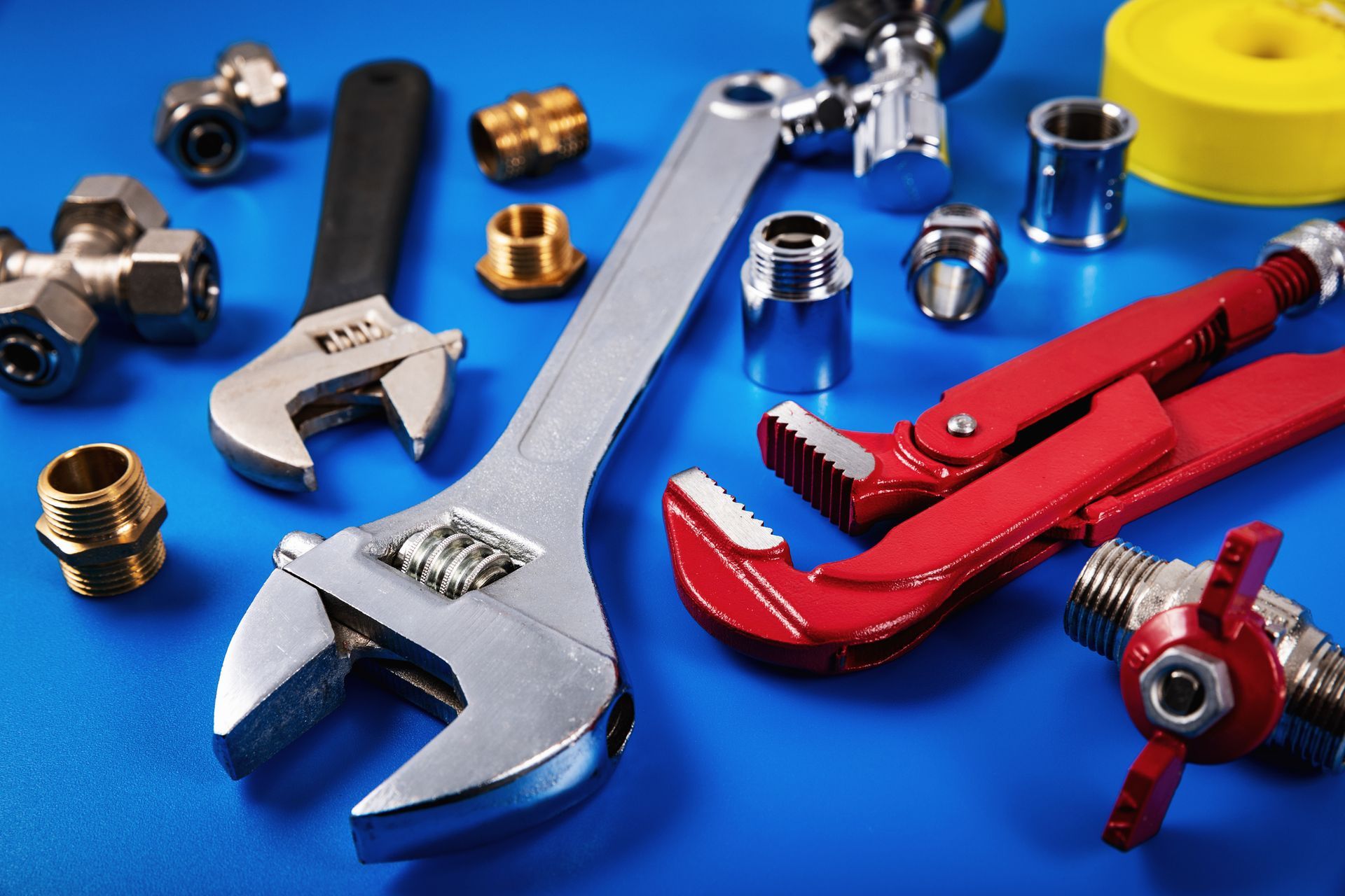 Plumbing tools and fittings, showcasing plumber service, with a large adjustable wrench ready. Plumbing tools and fittings, showcasing plumber service, with a large adjustable wrench ready.