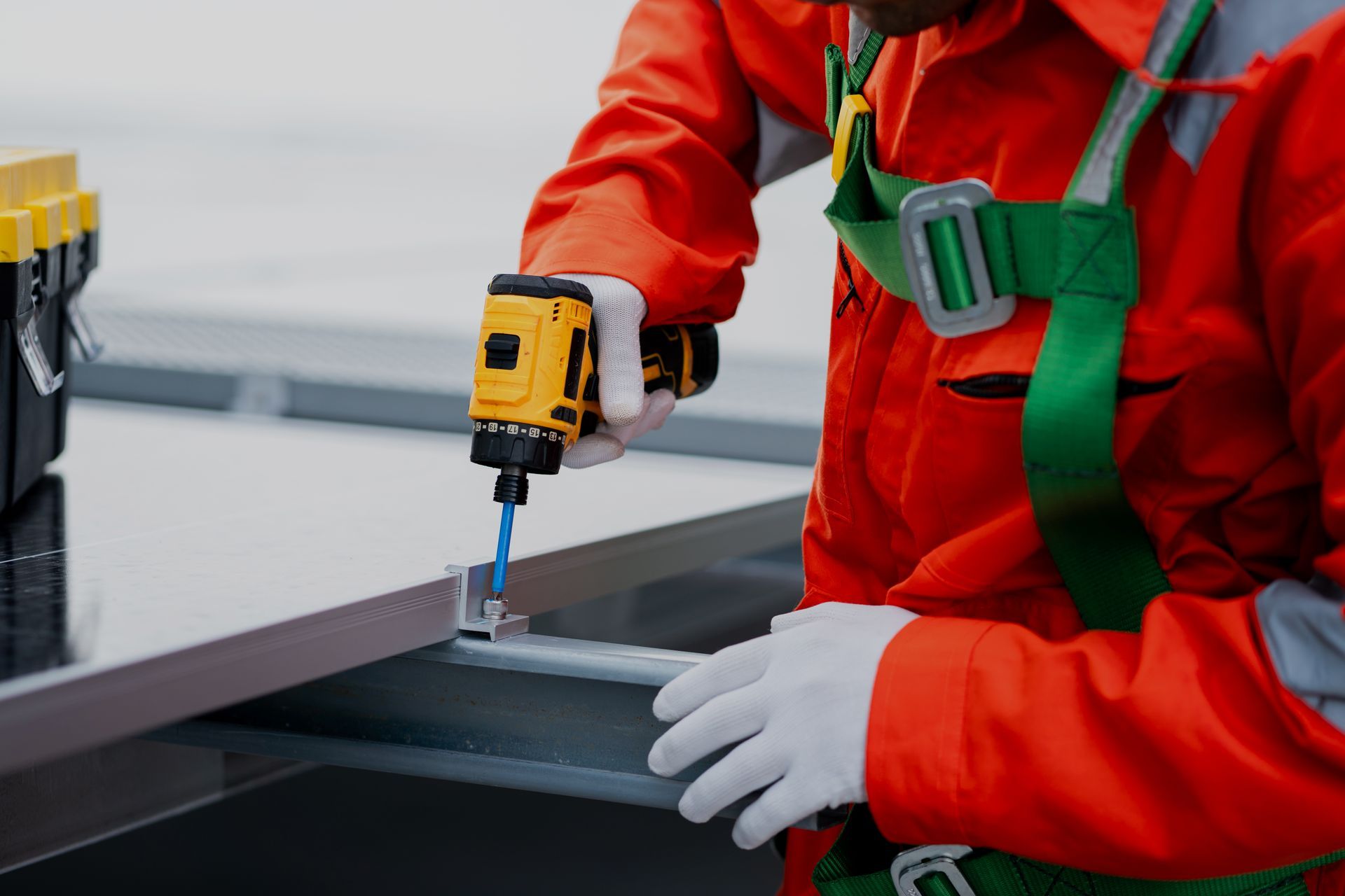 Two roofers in hard hats installing shingles on a house roof on a sunny day.