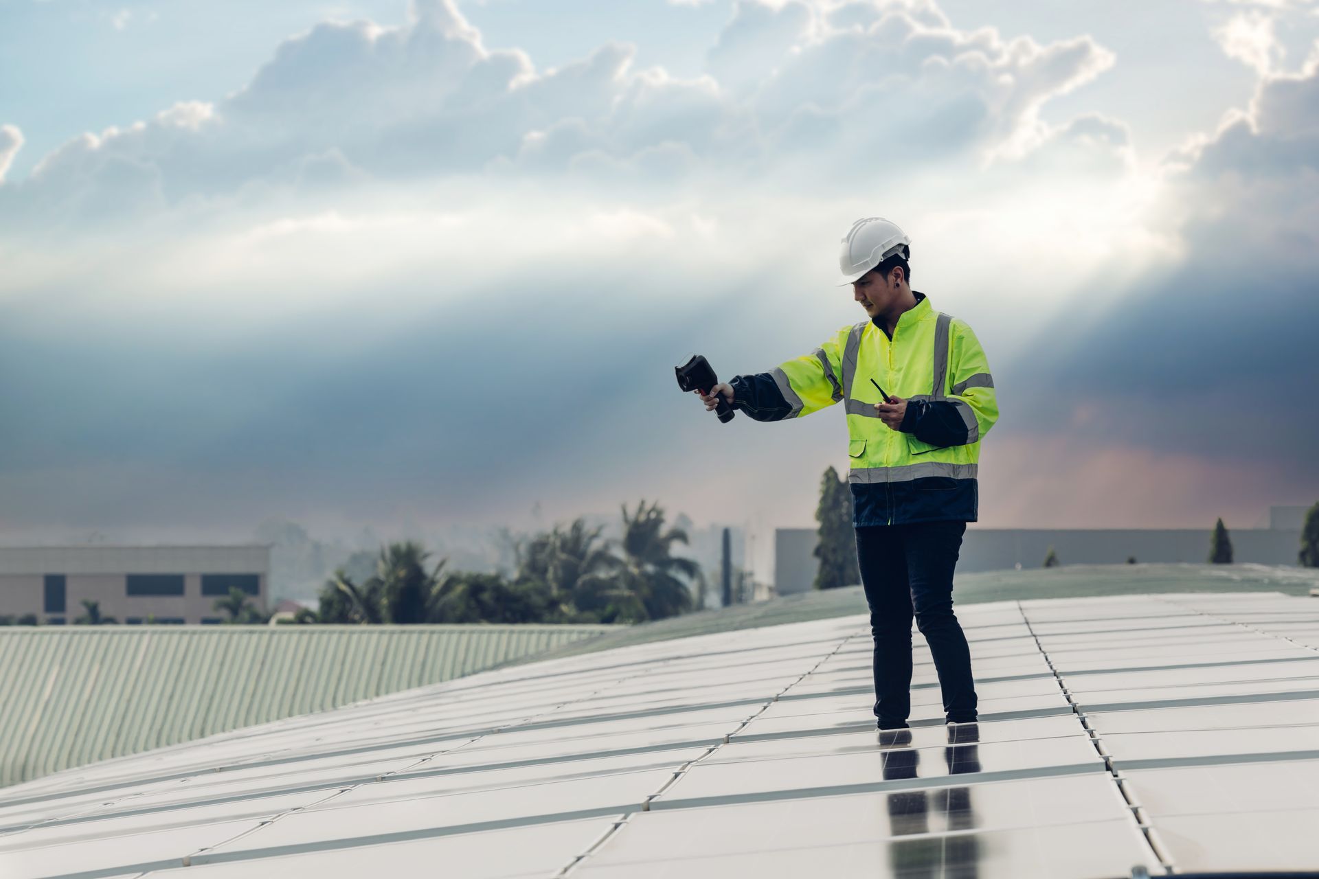 Man in hard hat and vest inspecting a roof, holding a clipboard.