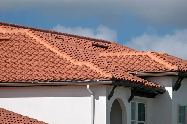 Person sits on a red tile roof with a dark, cloudy sky overhead.