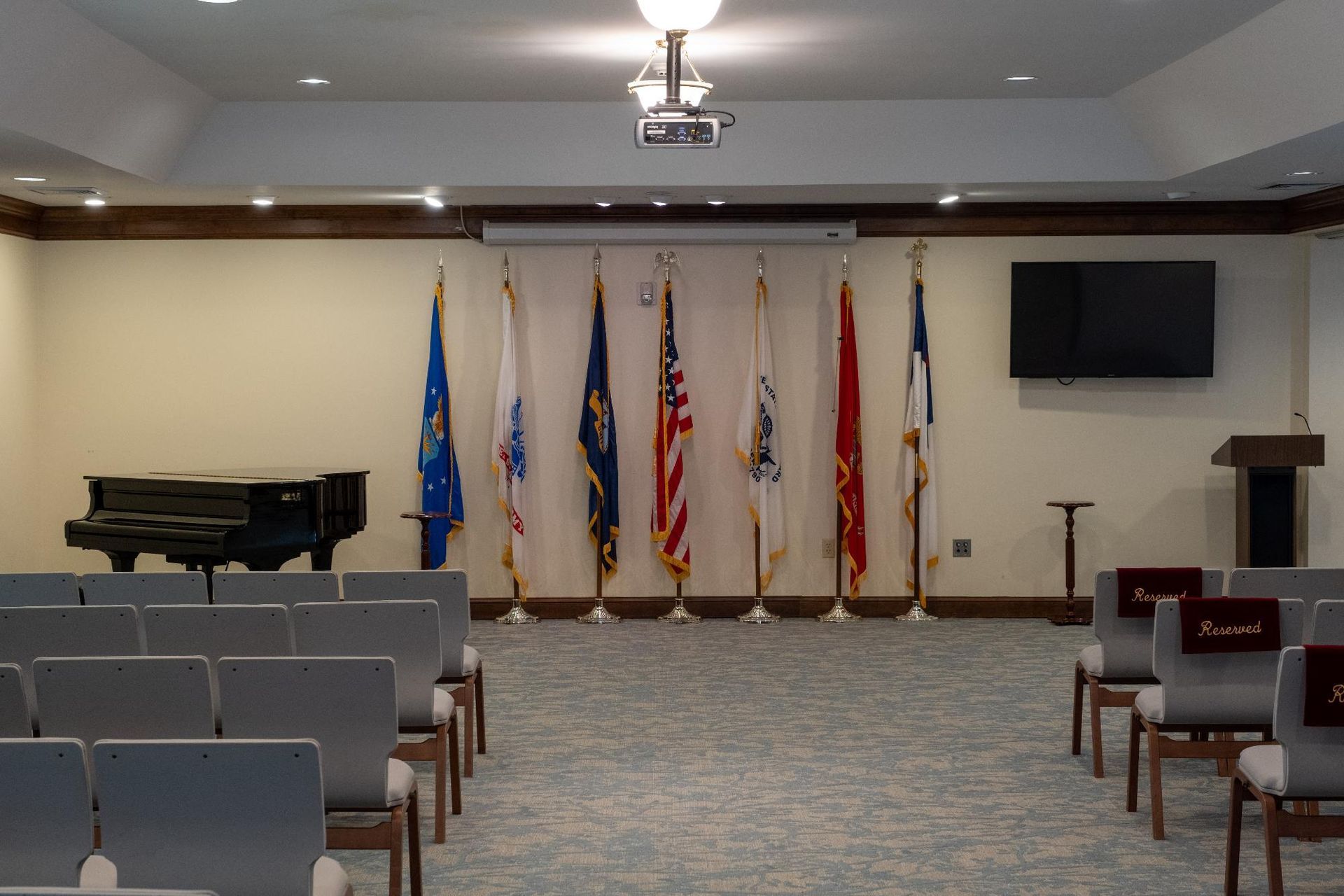 An empty auditorium with a piano and flags on the wall