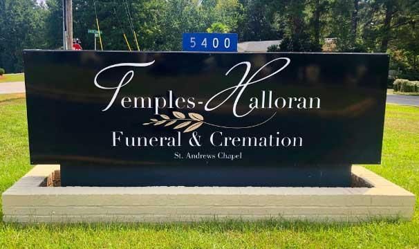 A large black sign for temples halloran funeral and cremation