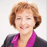 A woman in a suit and purple collar is smiling for the camera.