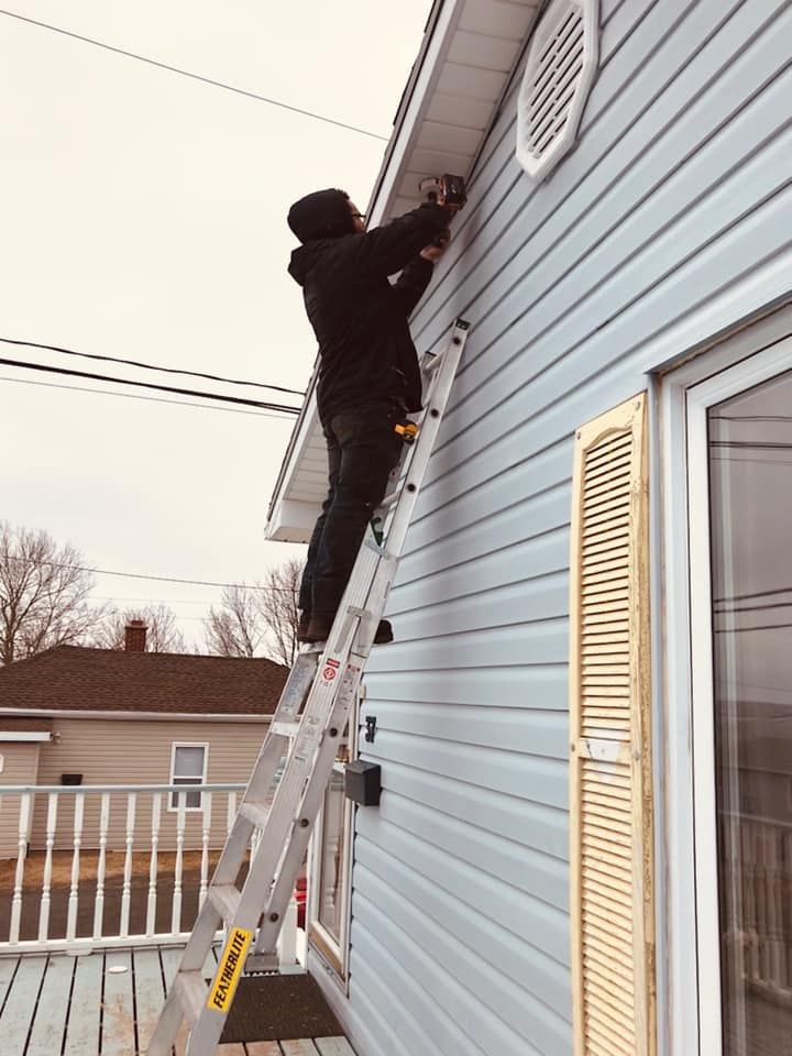 A man is standing on a ladder on the side of a house.