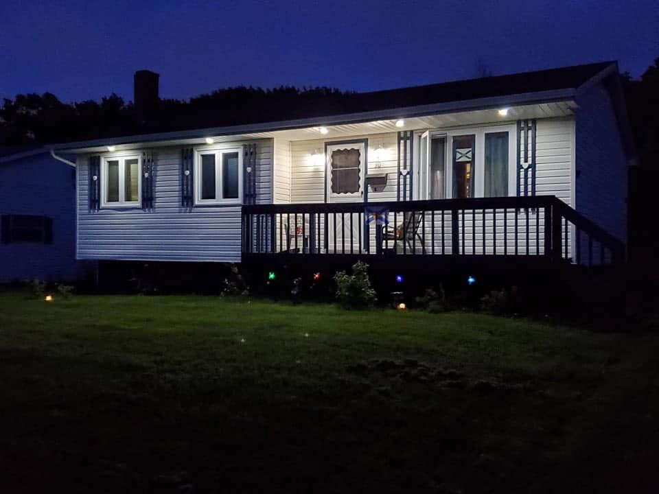 A house with a large deck is lit up at night.