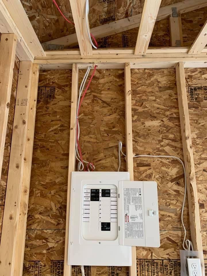 A electrical box is hanging from the ceiling of a house under construction.