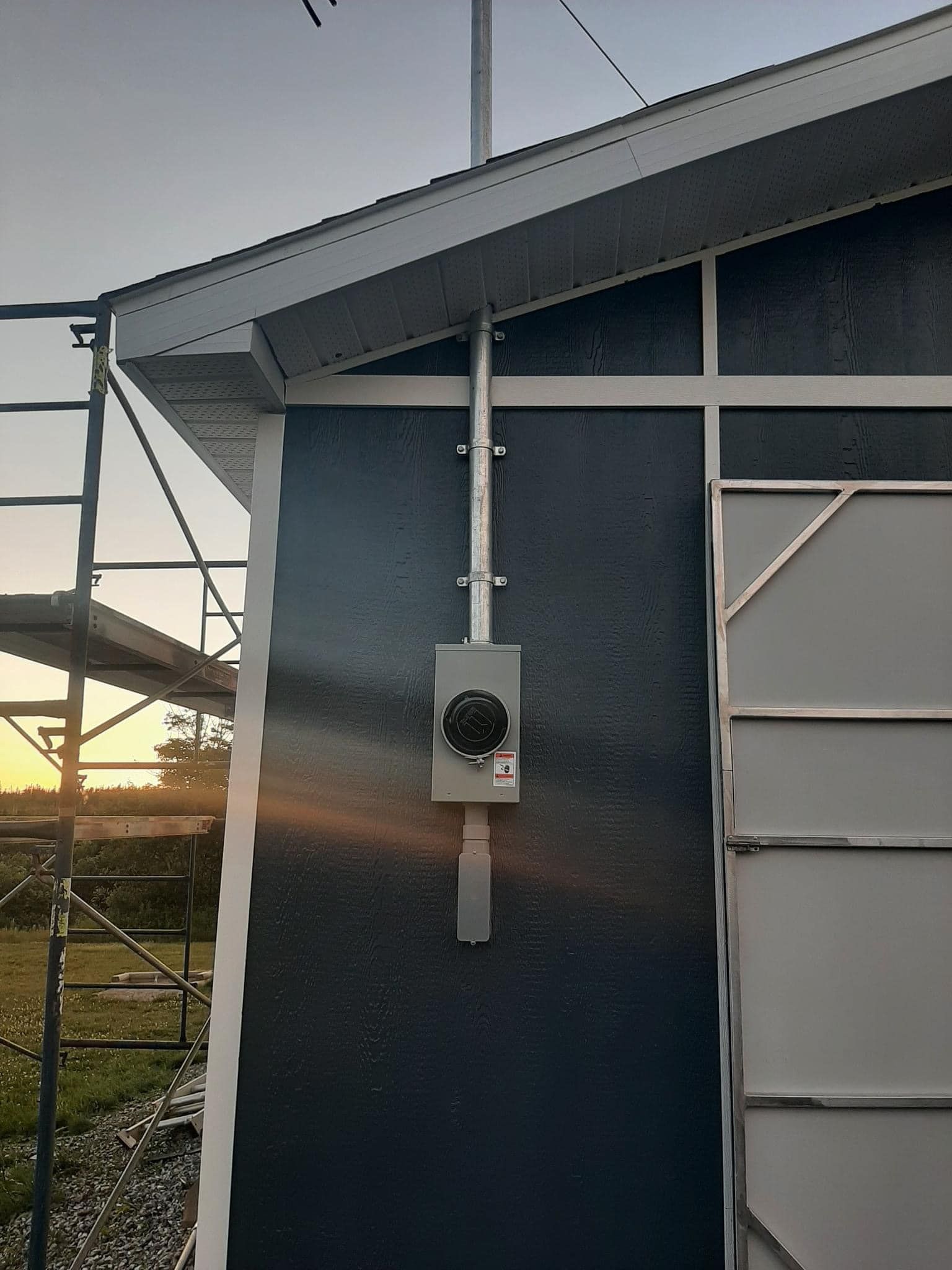 A blue building with a white door and a box on the side of it.