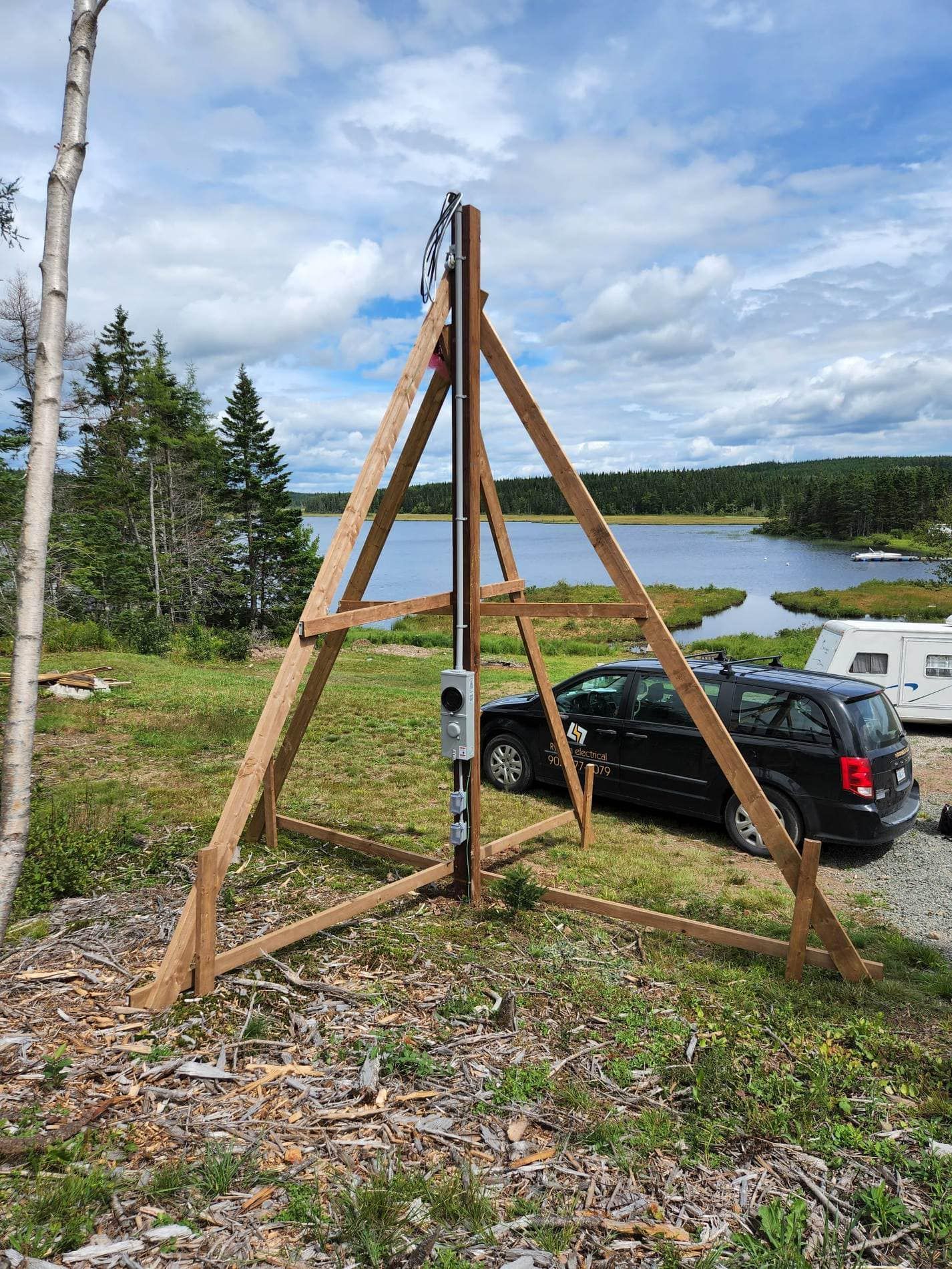 A wooden structure is sitting in the middle of a field next to a lake.
