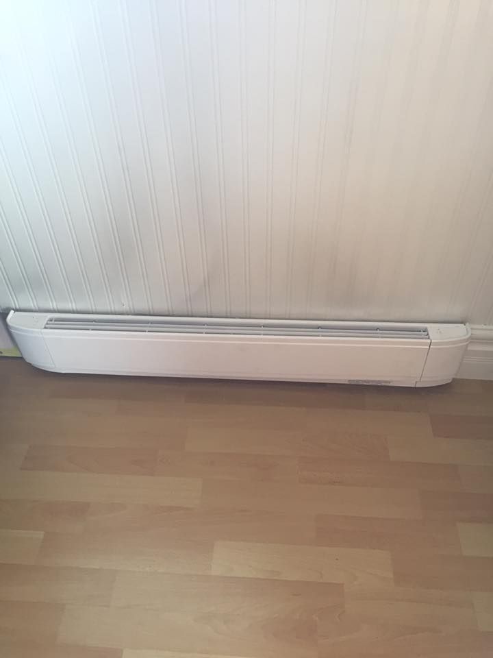 A white radiator is sitting on a wooden floor next to a wall.