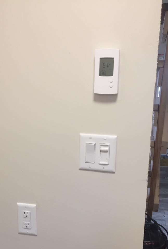 There is a thermostat and a light switch on the wall.