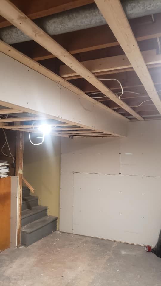 A basement under construction with stairs and a wooden ceiling.