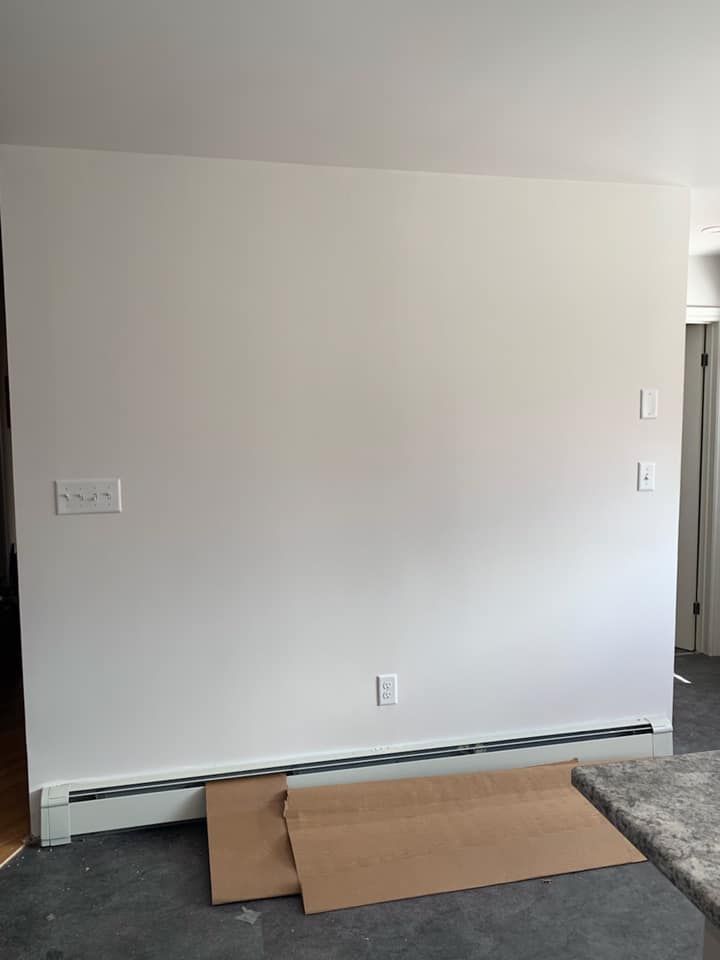 A room with a white wall and a cardboard box on the floor.