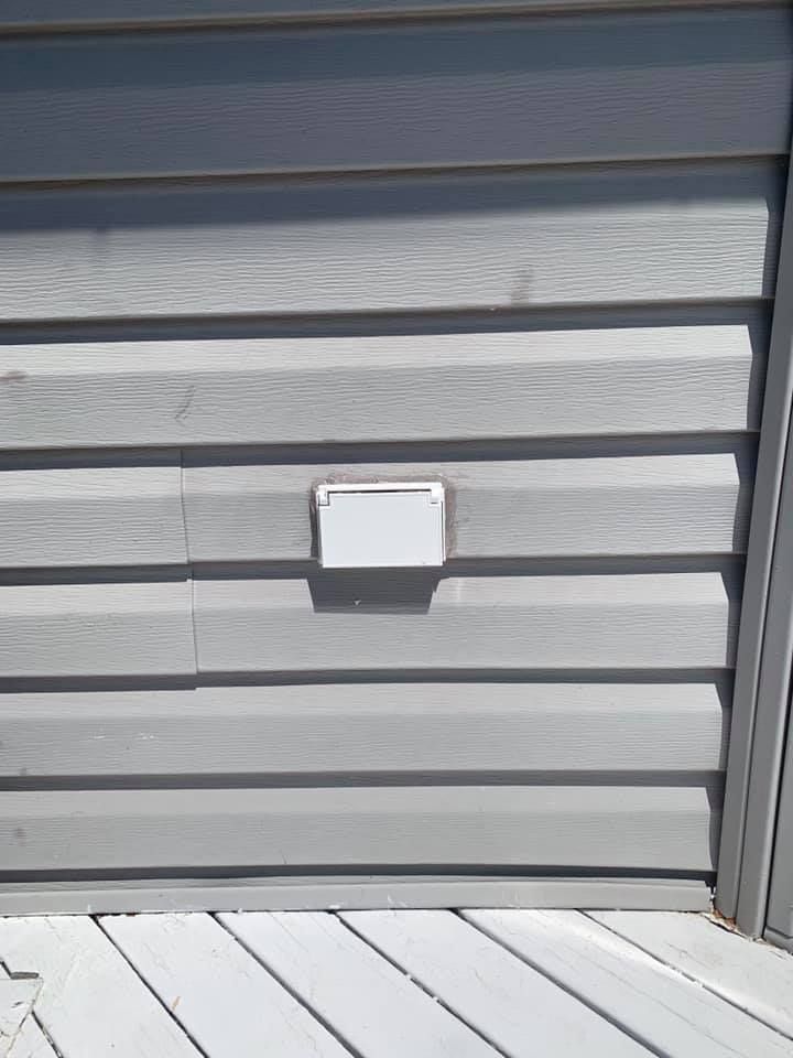 A gray siding on a house with a white light on it.