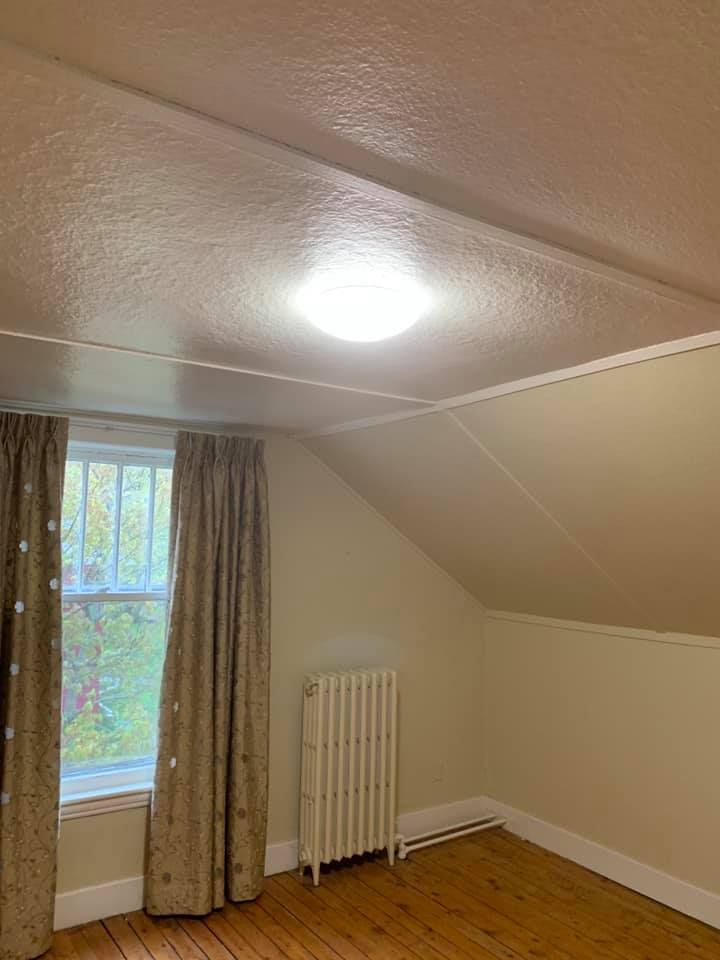 An empty room with a window and a radiator.