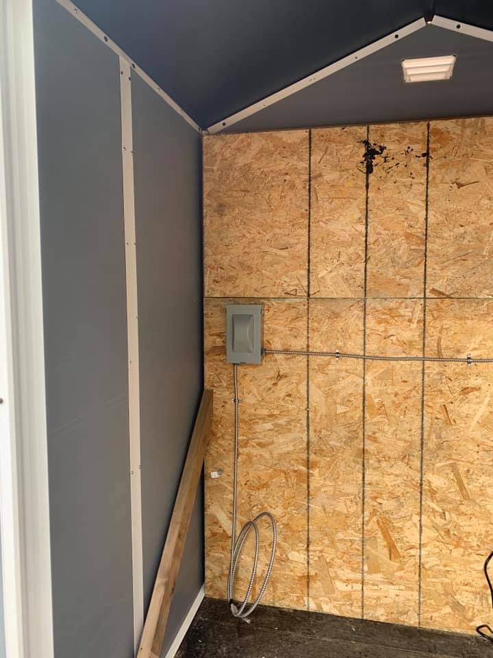 A shed with plywood walls and a light on the ceiling.
