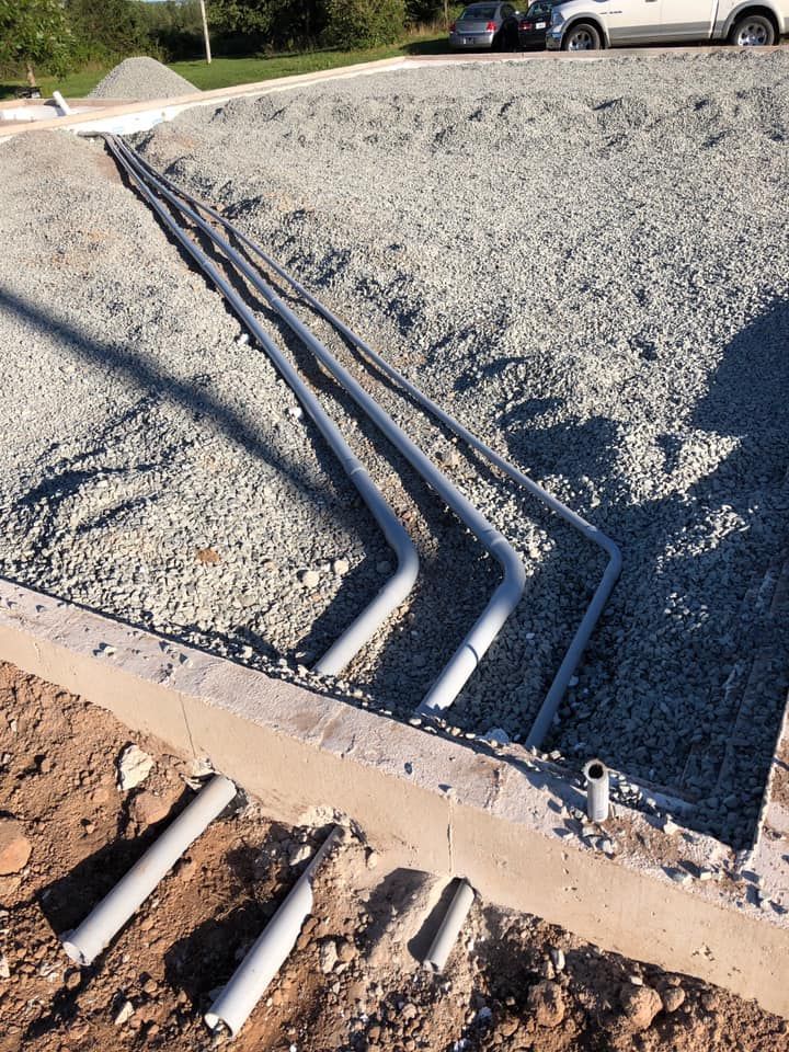 A bunch of pipes are laying in the dirt on the ground.
