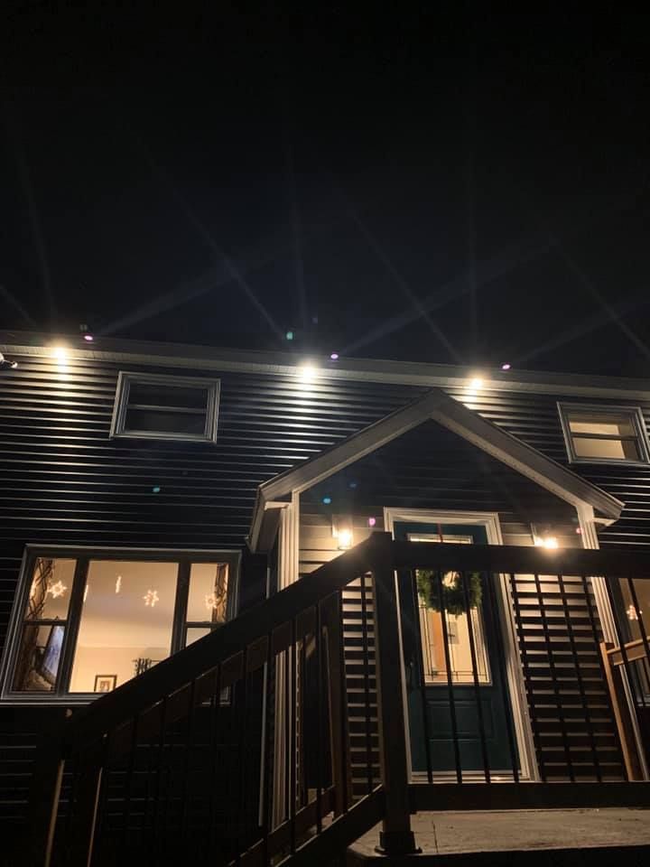 A house with a porch and stairs is lit up at night.
