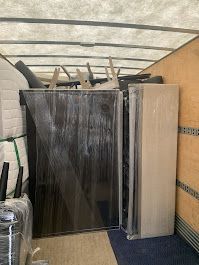 A truck filled with furniture and a refrigerator wrapped in plastic.